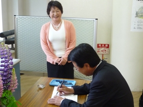 署名する市長と事務局の数藤和子さん