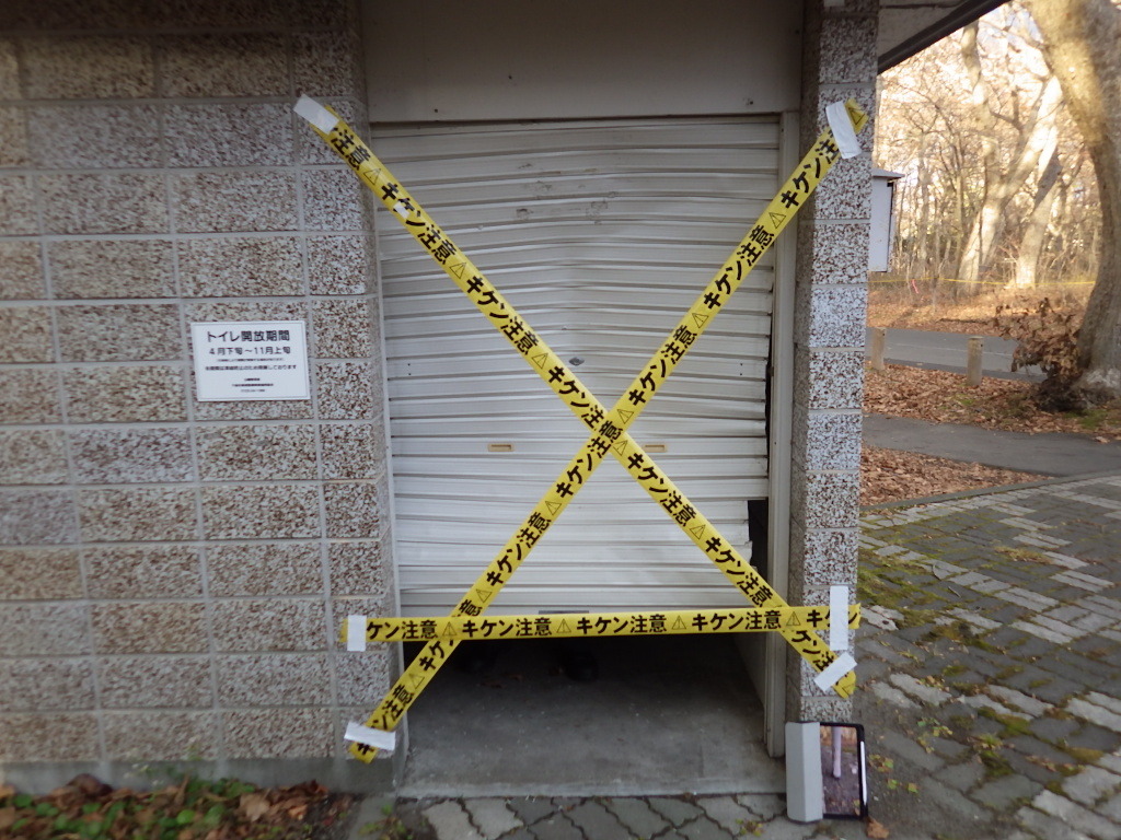 キケン注意と書かれた黄色いテープで注意喚起している損壊したのシャッターの写真