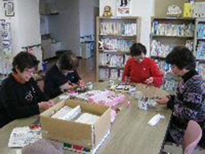 4人の支援ボランティアがピンクリボンを作成している写真