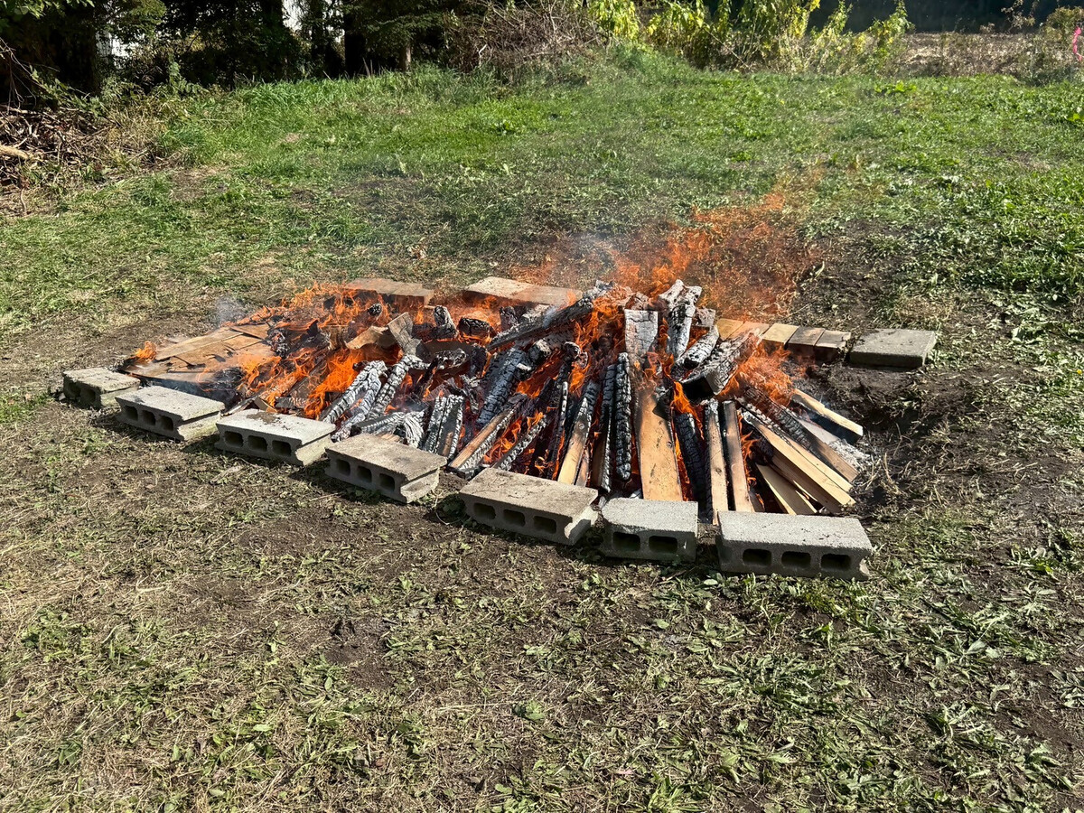 画面中央で、野焼きを行っています。炎の中は見えませんが、製作した土器が置かれています。