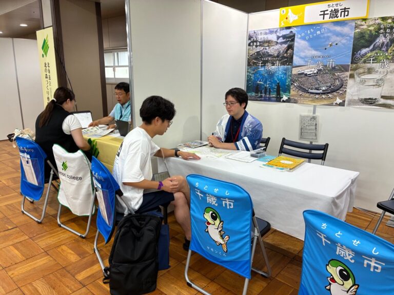 千歳市のブースで参加者に対応するスタッフの写真