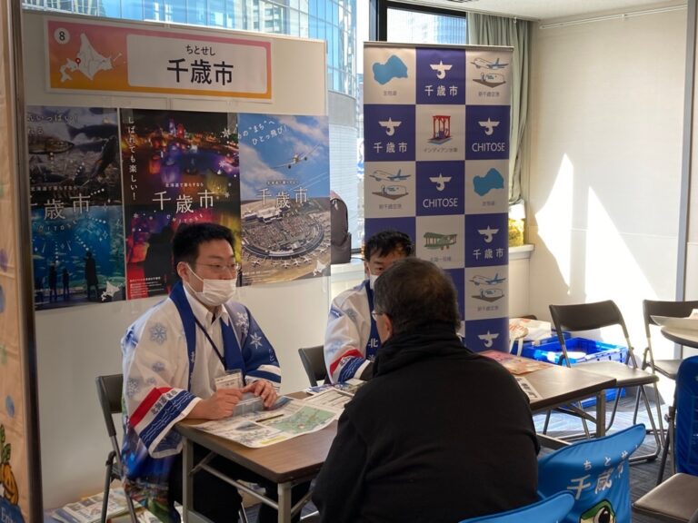 リーフレットを開いて参加者と懇談するスタッフの写真