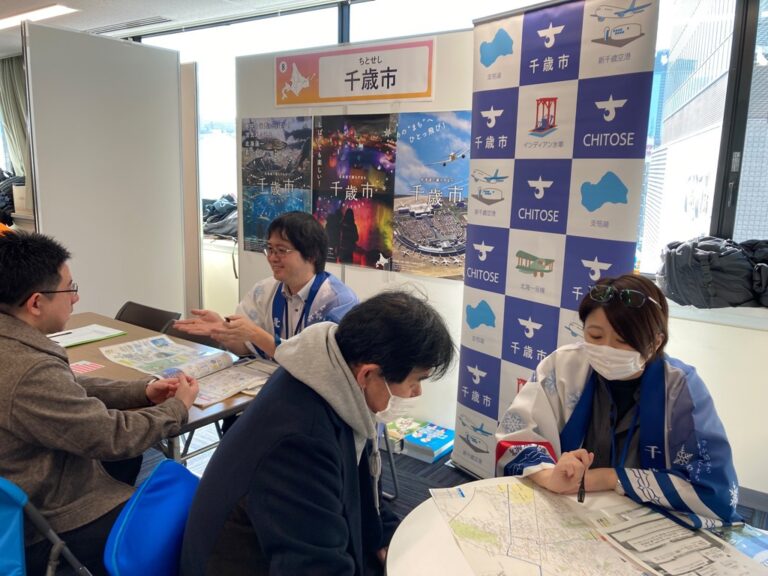 参加者と歓談する男性スタッフと、地図を広げて参加者に説明をする女性スタッフの写真