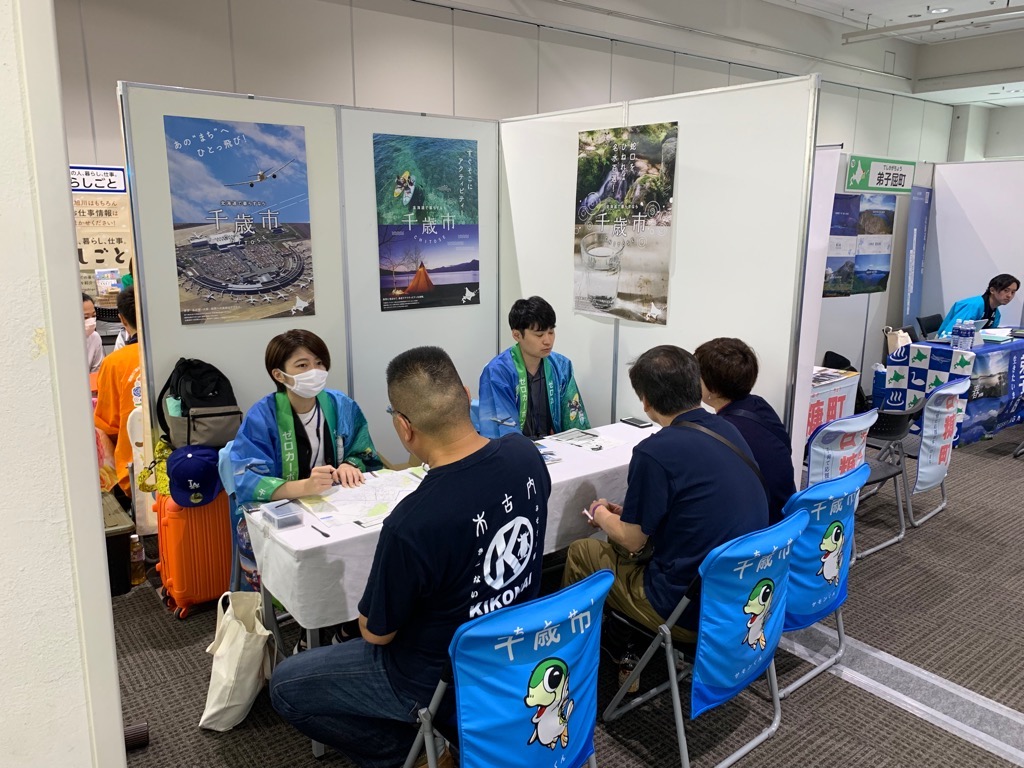 千歳市ブースで3人から相談を受けるスタッフ2人の写真